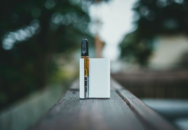 a white and brown vape pen on a wood surface